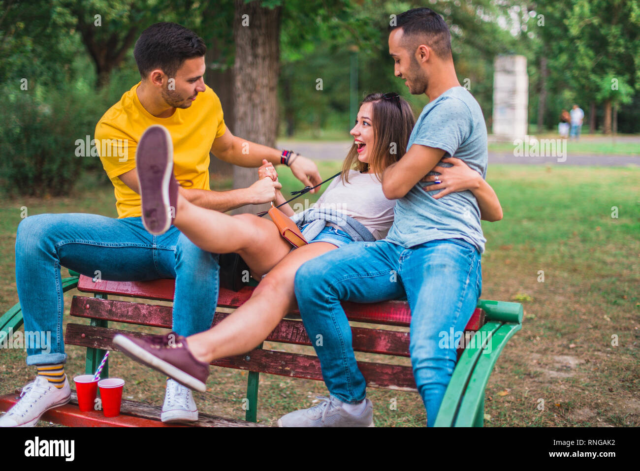 Freunde sitzen auf einer Bank im Park, Witze und Spaß haben Stockfoto