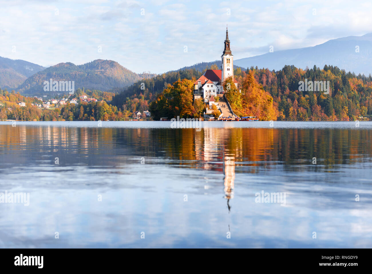 Bunte Herbst Blick auf See von Bled in den Julischen Alpen, Slowenien. Wallfahrtskirche der Himmelfahrt der Maria im Vordergrund. Landschaftsfotografie Stockfoto