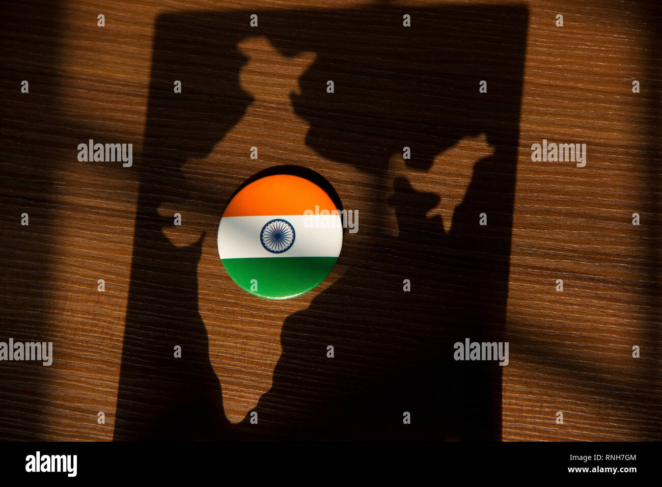 Indien Flagge Abzeichen gehalten auf braunem Hintergrund im Schatten des Indischen Karte Stockfoto