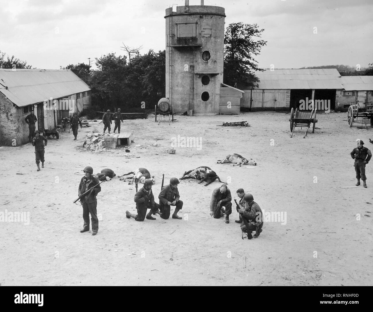 [ORIGINAL CAPTION] Invasion der Alliierten in Frankreich... Im Hof eines Bauernhauses sie gerade der Deutschen Scharfschützen gelöscht haben, die amerikanischen Truppen planen den Angriff der nächsten Ziel auf dem Weg zum Sieg, auf einen Brückenkopf von Frankreich. Juni 10, 1944. Les Dunes De Varredille [Varreville]. Stockfoto