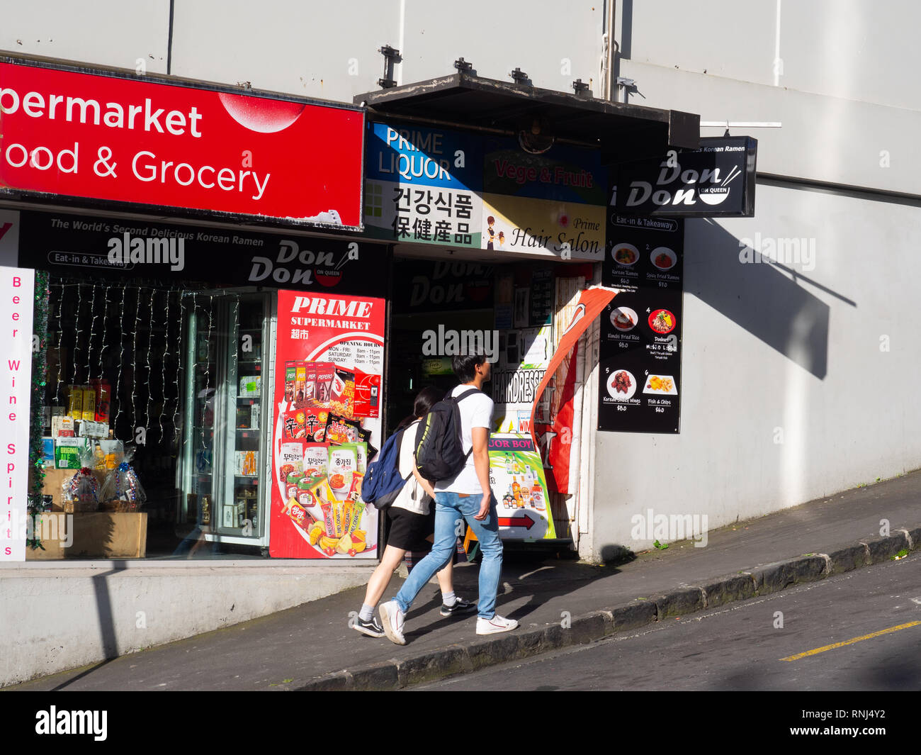 Menschen zu Fuß hinter einem Convenience Store Stockfoto