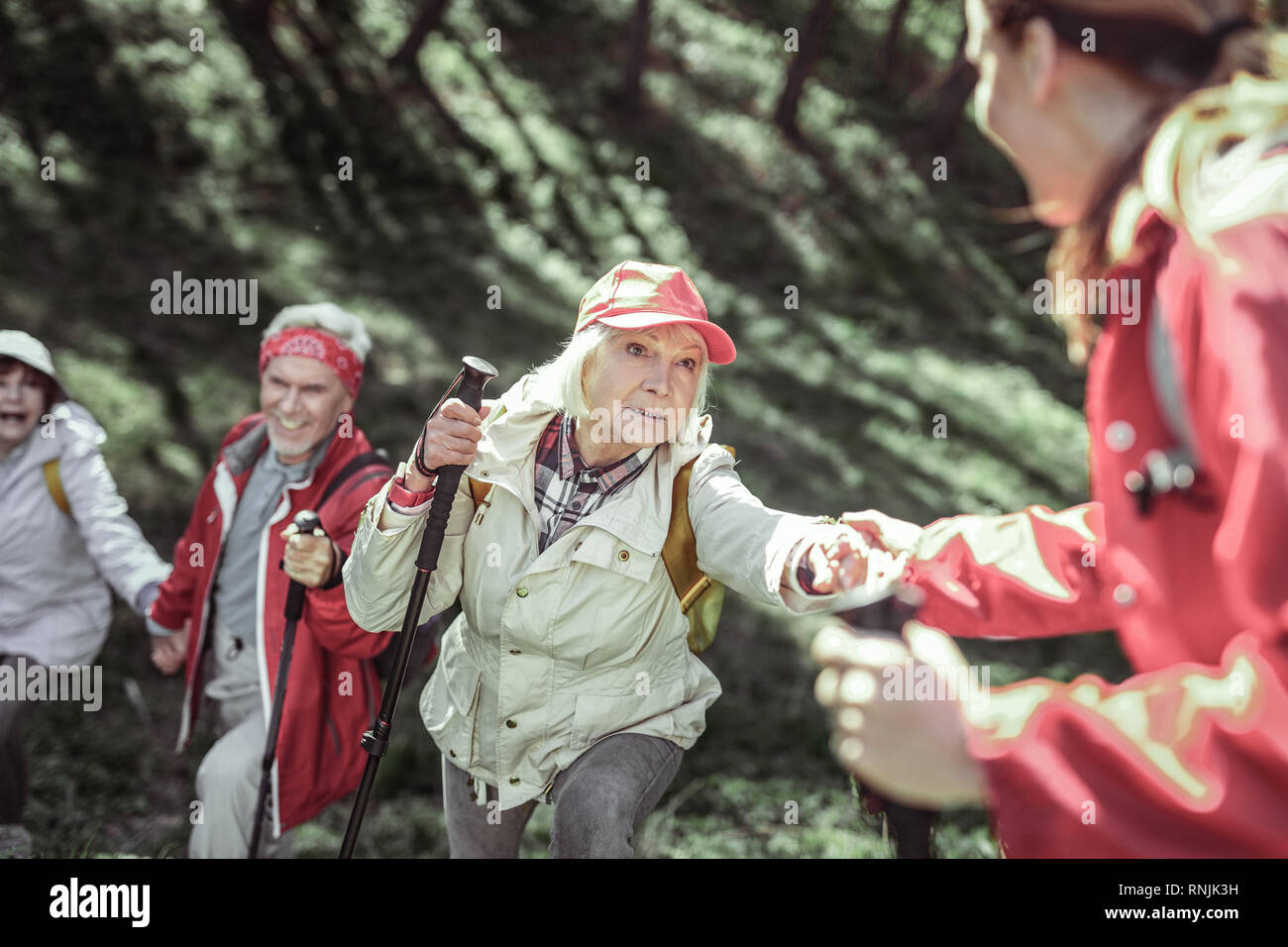 Starke junge Trainer tun Übung mit alten Menschen Stockfoto