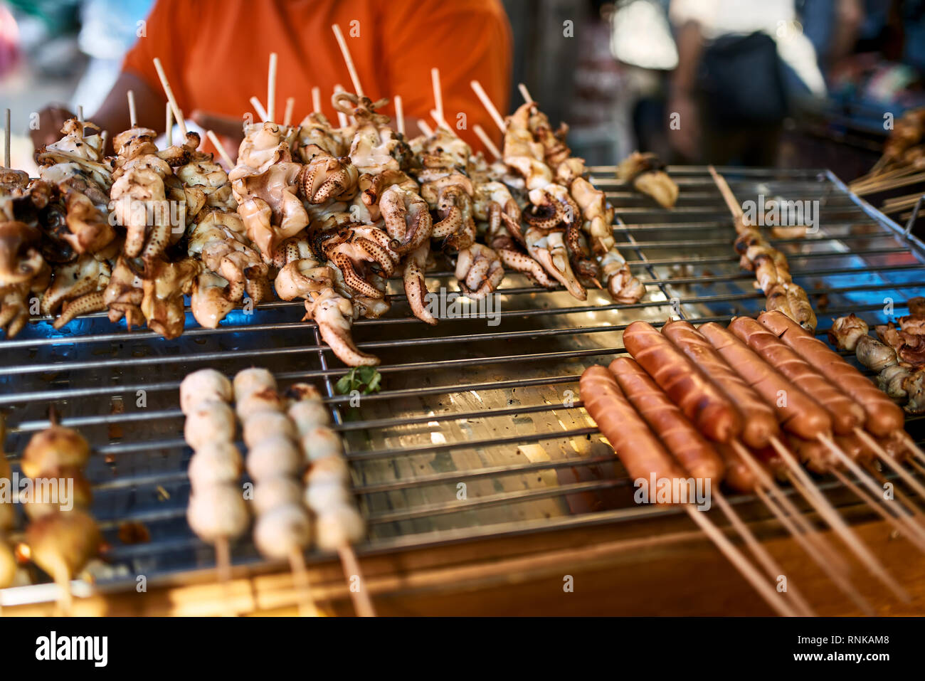 Asiatische Street Food präsentieren auf dem Markt in Bangkok, Thailand. Es gibt Sticks mit gebratenen Tintenfische, Fleisch- und Wurstwaren. Closeup horizontale Foto. Stockfoto