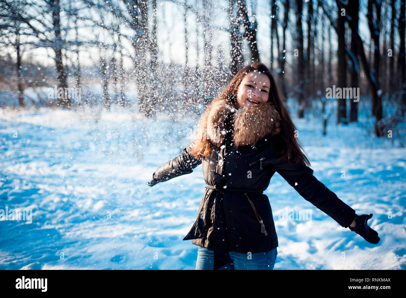 Hübsches Mädchen wirft Schnee im Winter Park Stockfoto