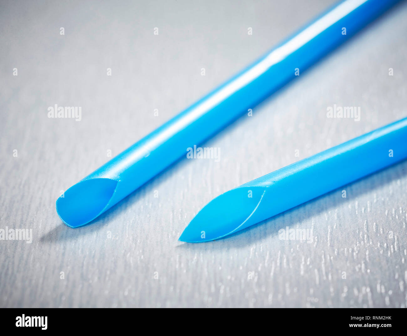 Zwei blaue Plastik Trinkhalme auf grauem Hintergrund. Studio Bild Stockfoto