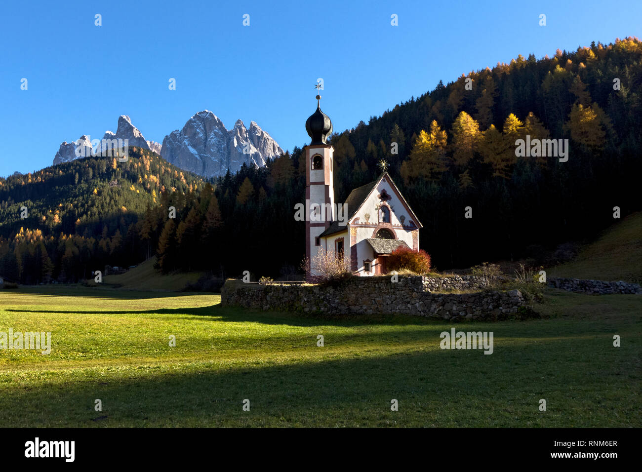 Die Kirche von San Giovanni in Ranui, Villnöss Tal. Im Hintergrund die Bergkette der Geislergruppe, Dolomiten. Stockfoto