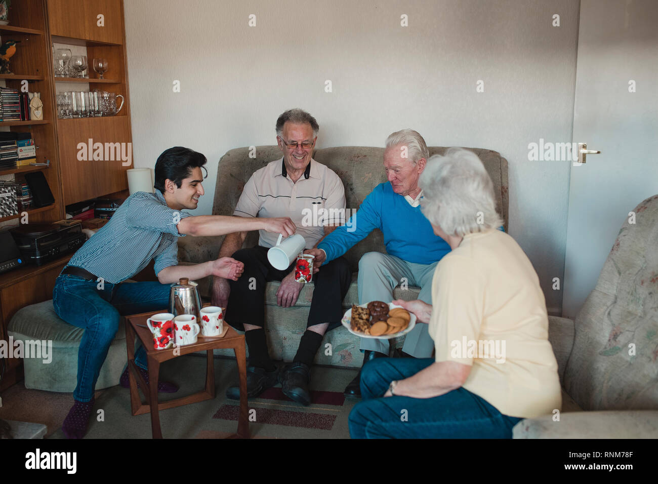 Teenager unterstützt ältere Erwachsene mit einem Tea Party in einem Pflegeheim. Stockfoto