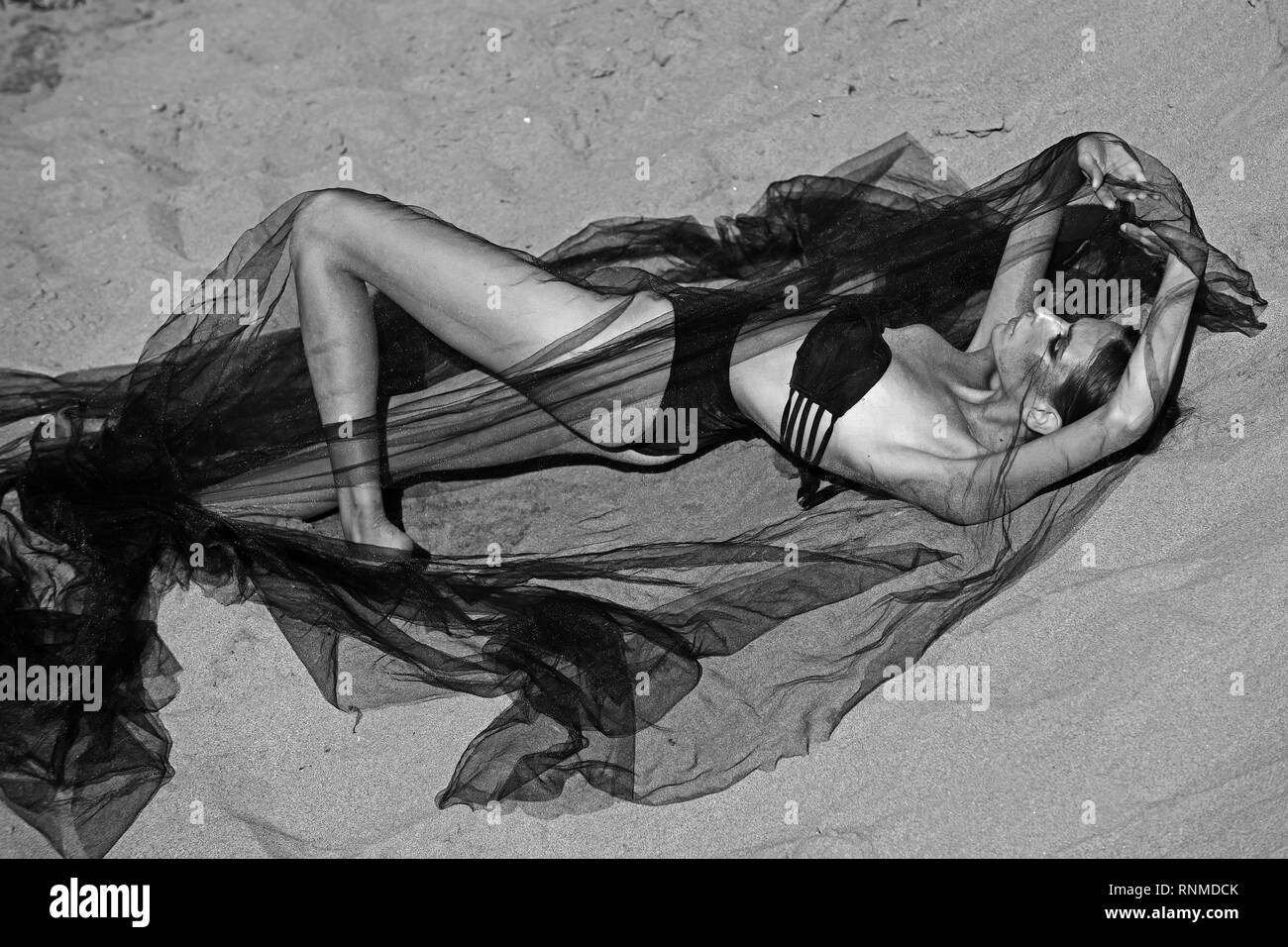 Mode Frau im Badeanzug unter schwarzen Schleier auf Sand entspannen Stockfoto