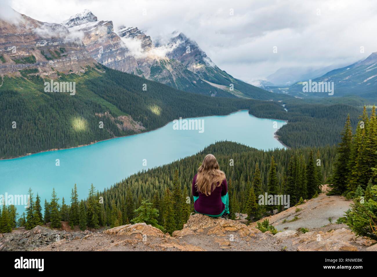 Junge Frau sitzt auf einem Stein in der Natur suchen, türkisfarbenen See, Peyto Lake, Rocky Mountains, Banff National Park, Alberta, Kanada, Nord Provinz Stockfoto