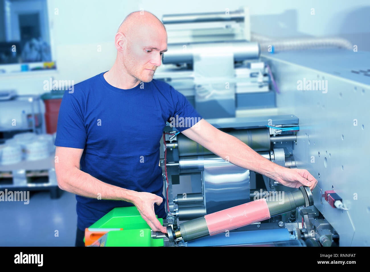Drucker der Fahrer neben der Druckmaschine, Druckzylinder mit Polymer relief Platte stecken. Szene mit der Vorbereitung für die Stockfoto