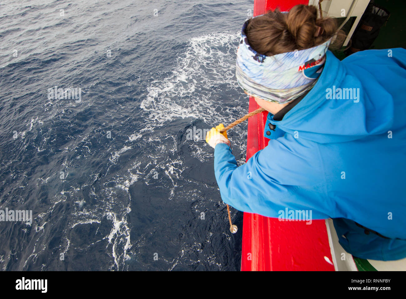 Ein Forscher Tropfen einen Eimer Wasser über Bord Proben auf einem Forschungsschiff Durchführung einer wissenschaftlichen ozeanographischen Kreuzfahrt im Südatlantik zu sammeln Stockfoto