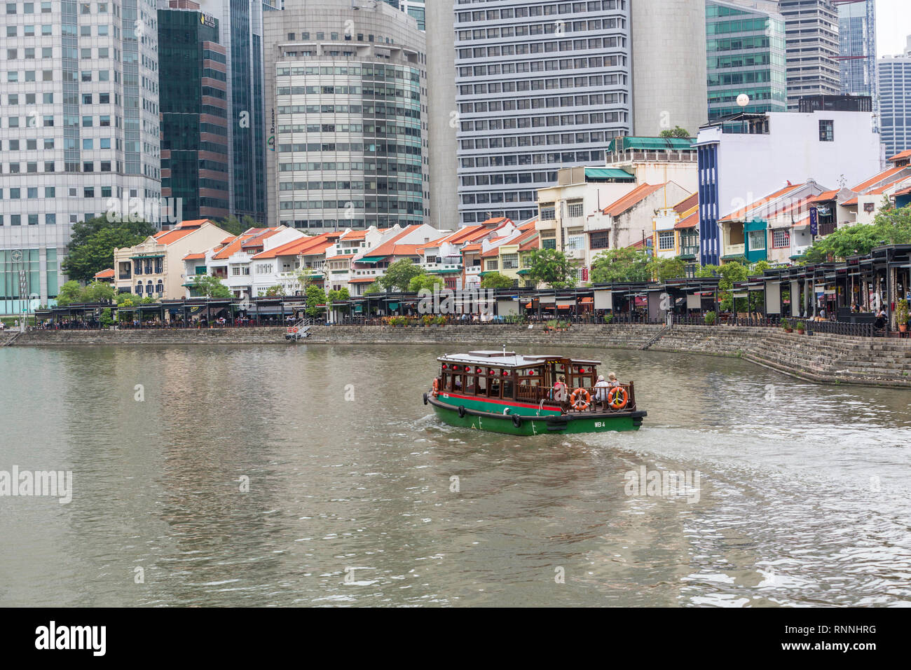 Wasser Taxi auf dem Singapore River. Boat Quay, ehemaligen Shop Häuser jetzt Restaurants und Bars. Gebäude der Financial District im Hintergrund. Singapur. Stockfoto