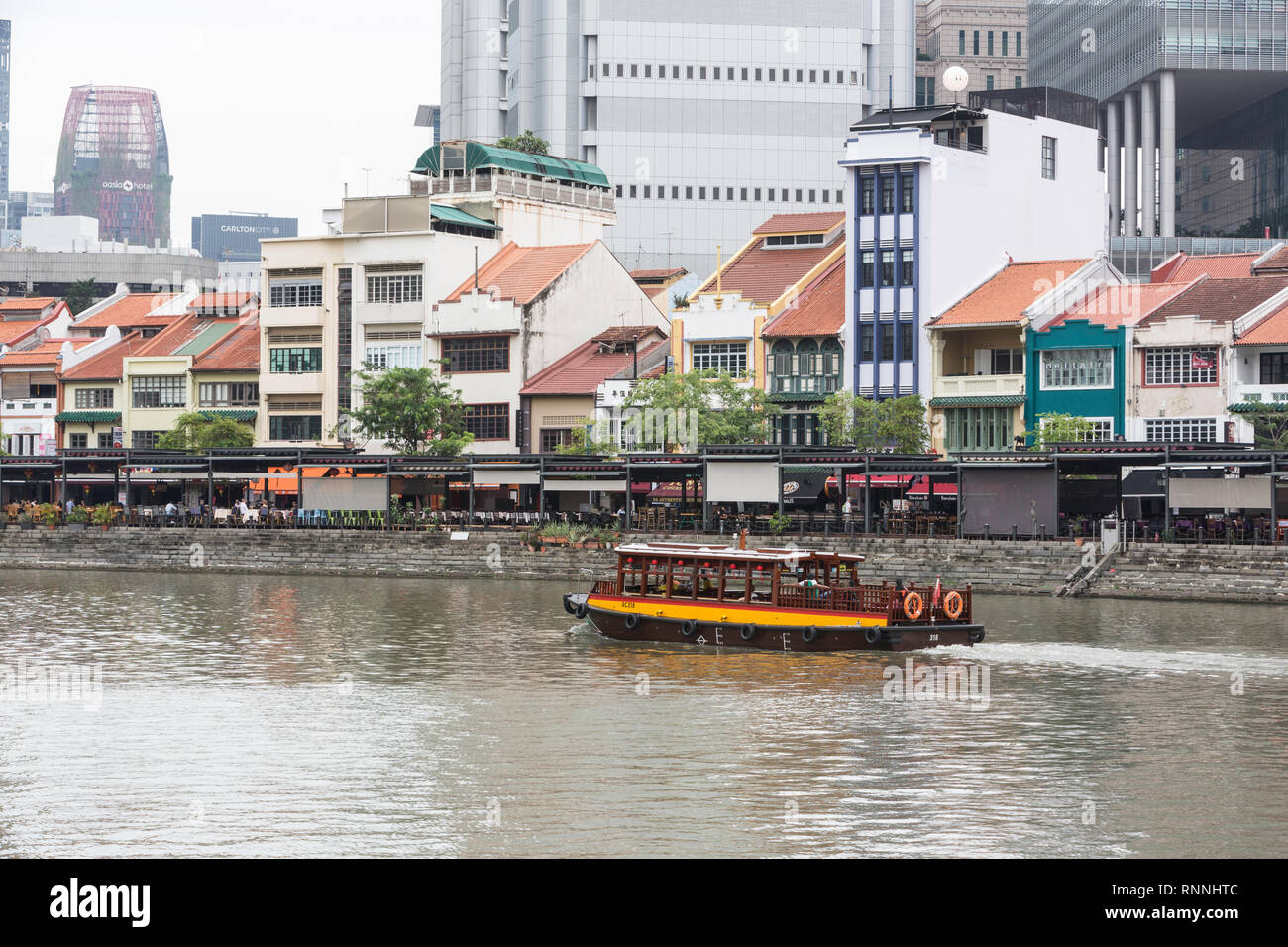 Wasser Taxi auf dem Singapore River. Boat Quay, ehemaligen Shop Häuser jetzt Restaurants und Bars. Gebäude der Financial District im Hintergrund. Singapur. Stockfoto