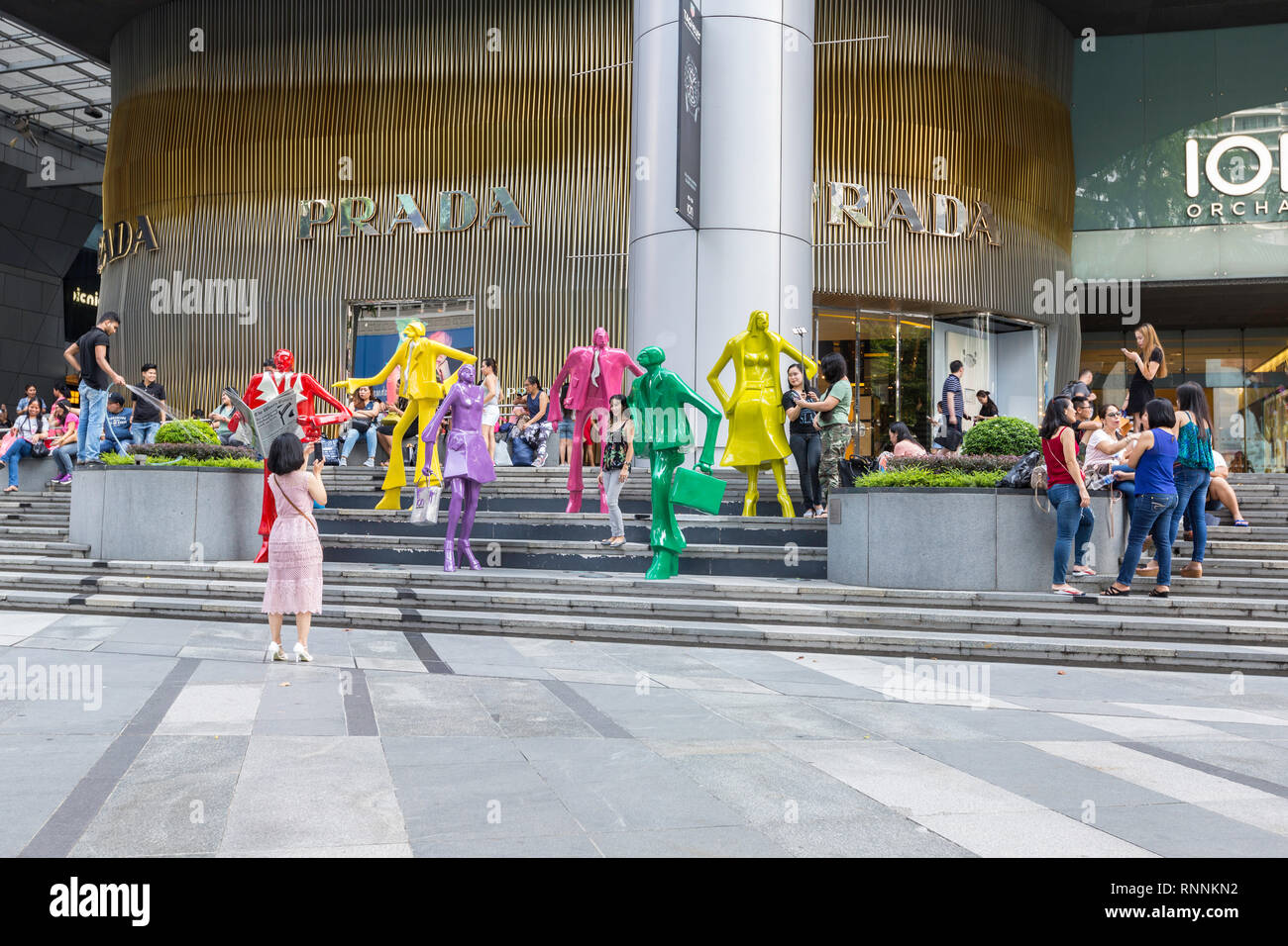 Von Singapur, der Orchard Road Street Scene. Touristen posieren für Fotos inmitten moderner Skulptur außerhalb ION Mall. Stockfoto