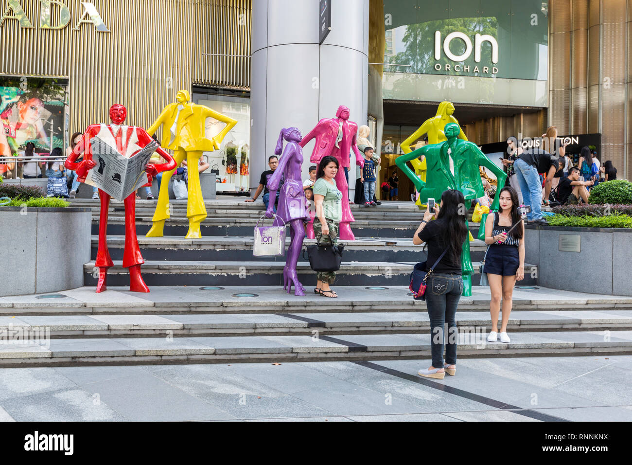 Von Singapur, der Orchard Road Street Scene. Touristen posieren für Fotos inmitten moderner Skulptur außerhalb ION Mall. Stockfoto