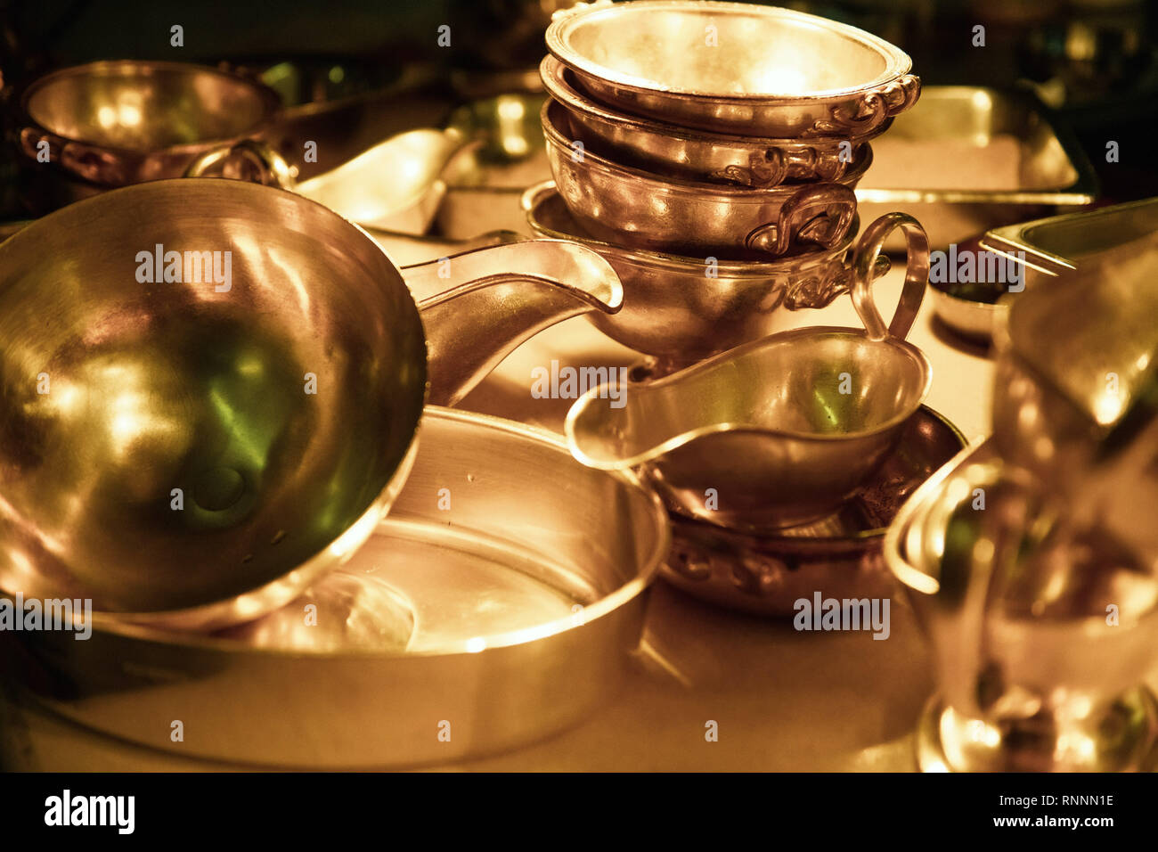 Schwere silberne Schalen und Sauce Schalen in goldenem Licht gestapelt. Stockfoto