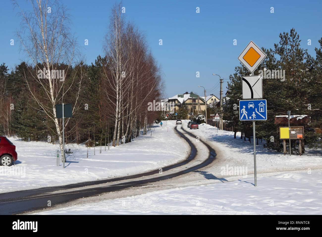 Verschneite winter Straße in einem no name Dorf und ein Einsamer Reisender März sonnigen Tag Landschaft Stockfoto