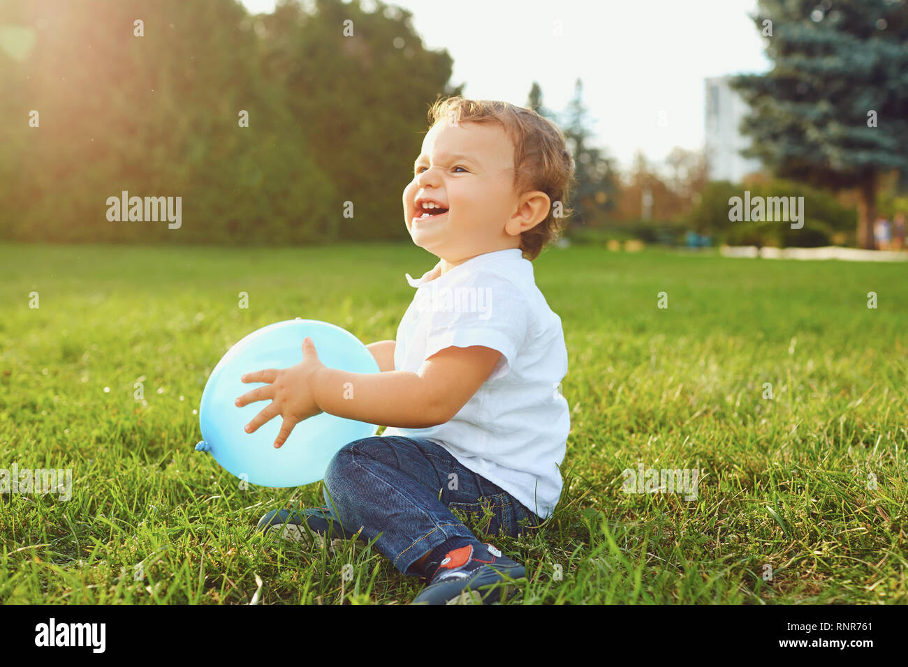 Kleiner Junge mit einem Ballon spielt, Lächeln auf dem Rasen im Park. Stockfoto