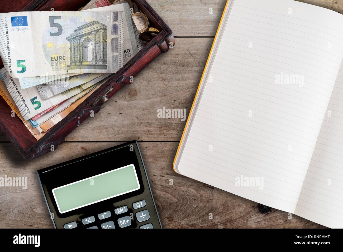 Finanzen und die allgemeine Ordnung und Sauberkeit Konzept mit offenen Leerbuch, Rechner und Holzbox mit Bargeld auf Tabelle ausgefüllt Stockfoto