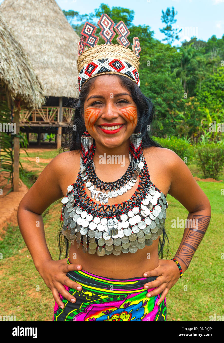 Porträt eines lächelnden Embera indigene Frau vor der traditionelle Gehäuse posiert in traditioneller Kleidung in der Nähe von Panama City, Panama, Mittelamerika. Stockfoto