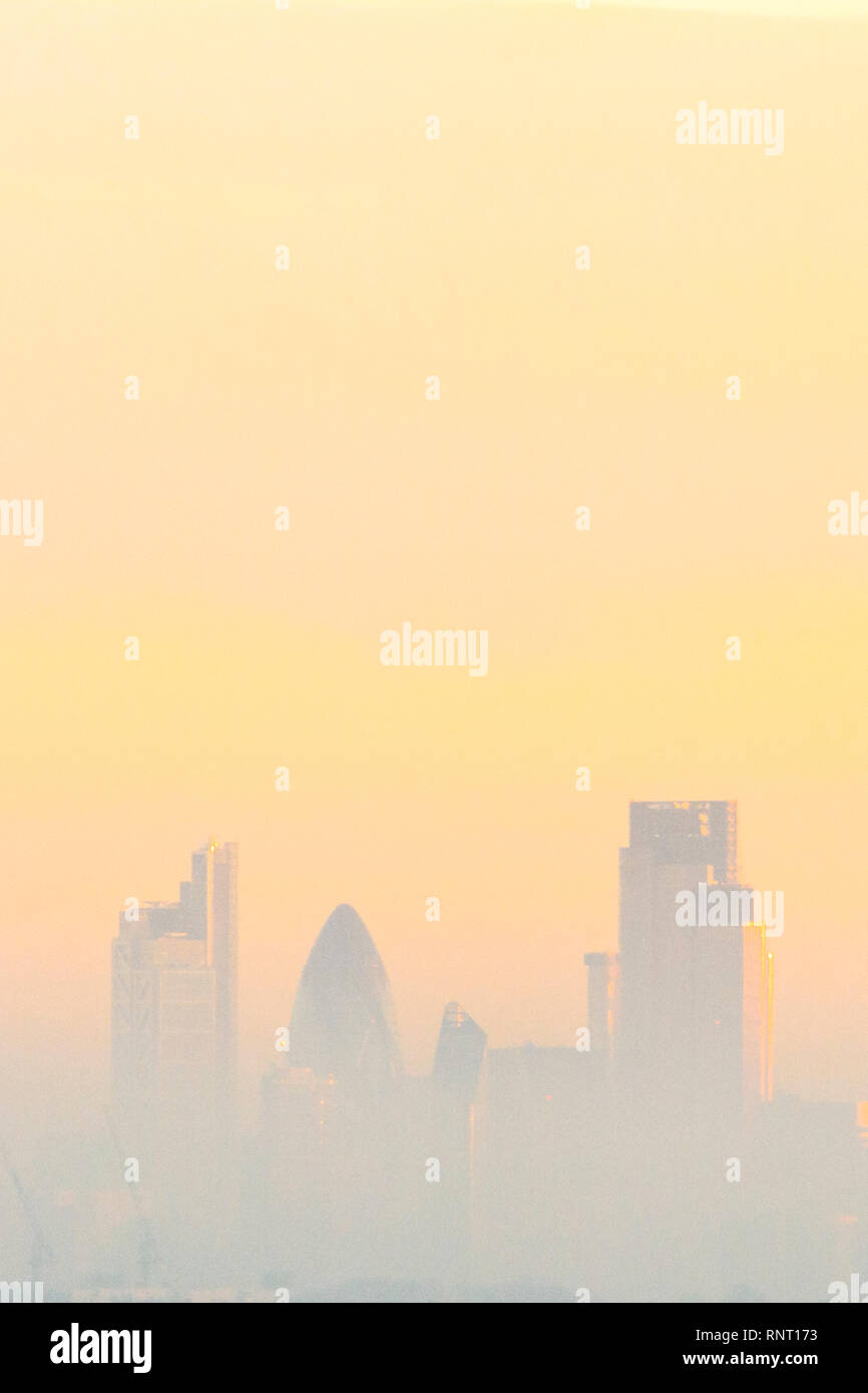 Hohe Gebäude in der City von London, durch Nebel und Umweltverschmutzung in den goldenen Glanz der Sonnenuntergang gesehen Stockfoto