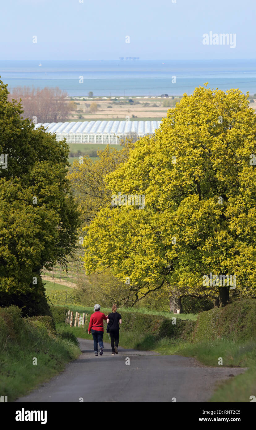 Eine Mutter und ihre Tochter zu Fuß auf einem schmalen Feldweg in Kent mit dem Thames Estuary im Hintergrund. Stockfoto