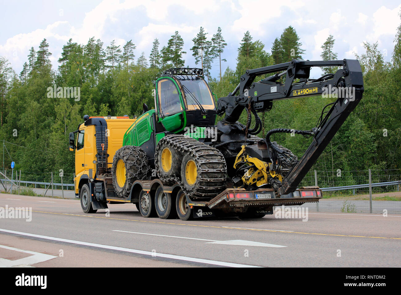 Orivesi, Finnland - 27. August 2018: Gelb Volvo LKW-Transporte neue John Deere Wald Spediteur am Anhänger auf der Autobahn im Sommer, Ansicht von hinten. Stockfoto
