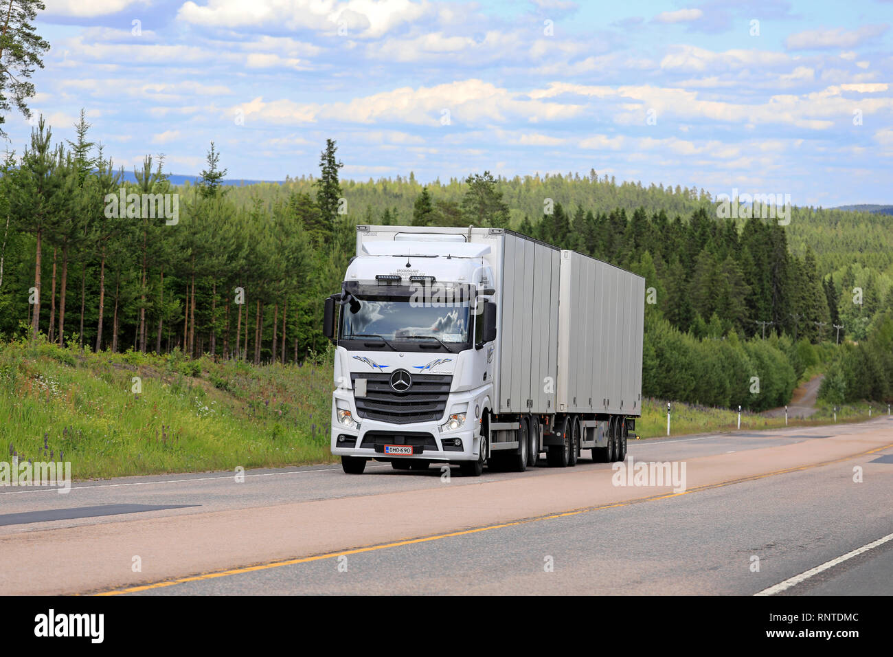 Jamsa, Finnland - 14. Juni 2018: Weiße Mercedes-Benz Actros Lkw Fracht zieht Trailer bergauf auf Scenic Highway an einem schönen Tag im Sommer. Stockfoto