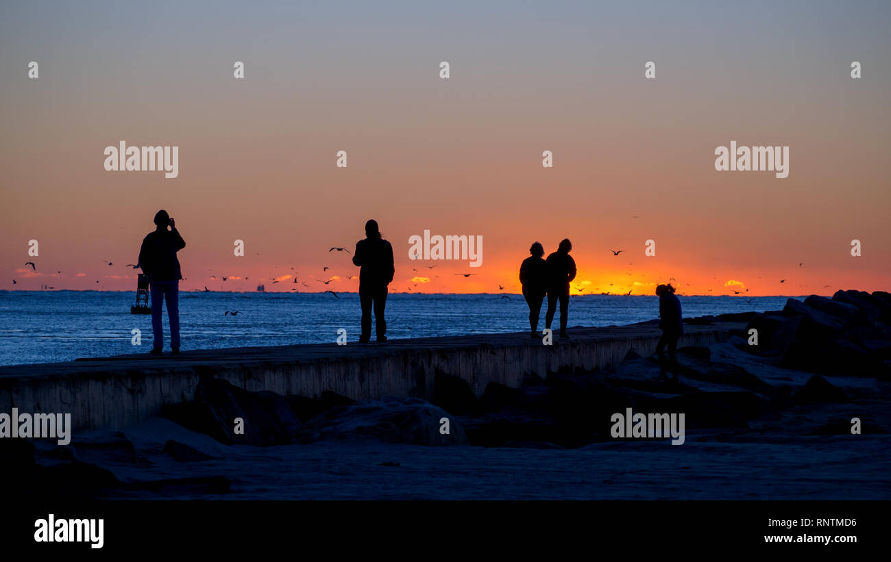 Eine Gruppe von Menschen auf dem South Pier in Port Aransas, Texas gegen den Himmel kurz vor Sonnenaufgang. Stockfoto
