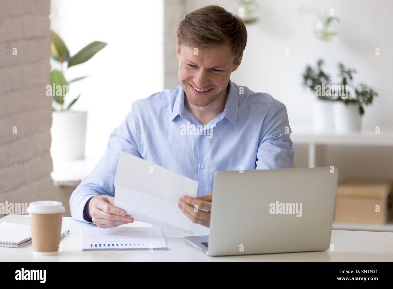 Zufriedene Unternehmer sitzen am Schreibtisch lesen schreiben Stockfoto