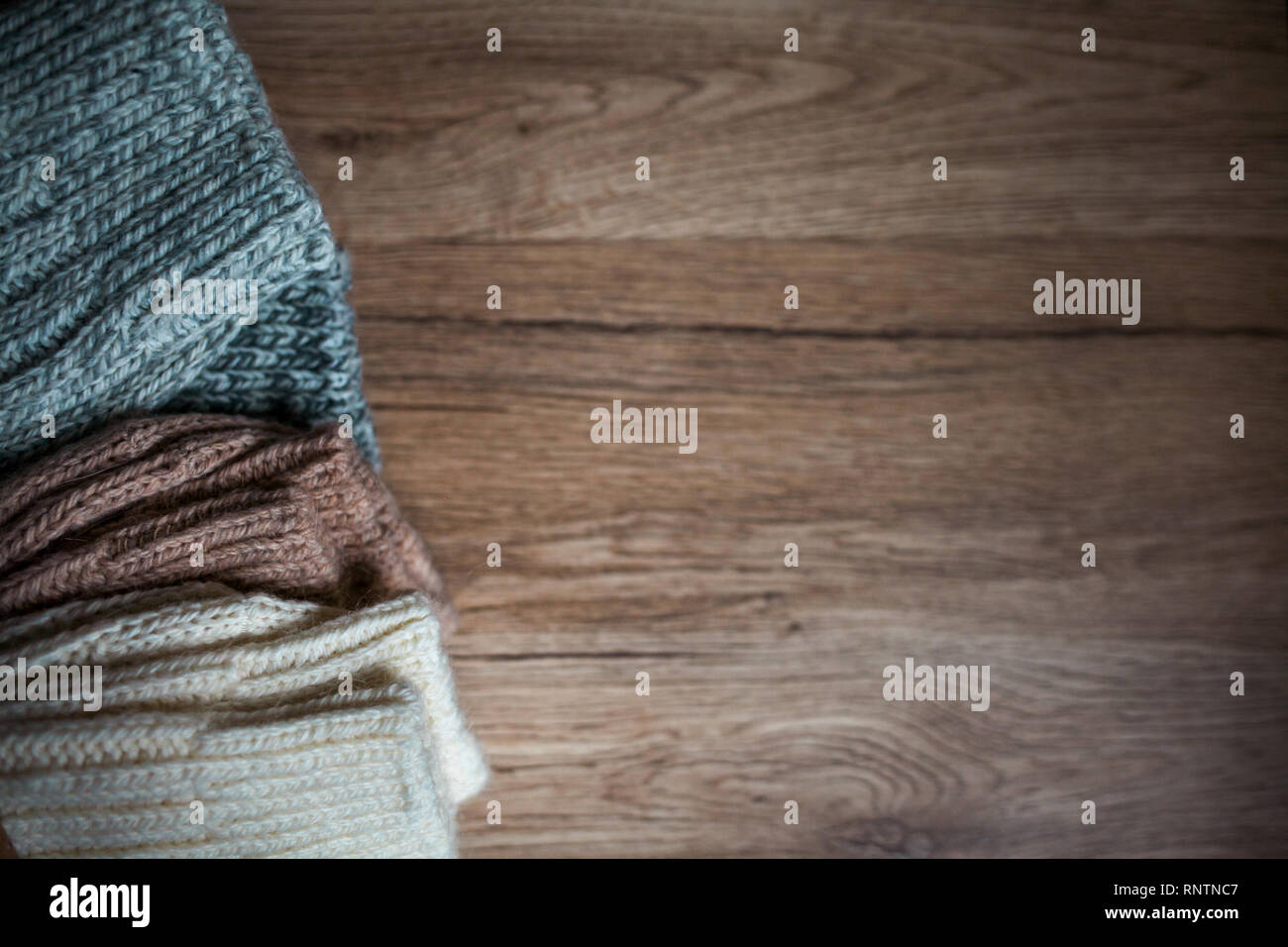 Stapel von gemütlichen gestrickte Wolle Kleidung auf einem Holz- Hintergrund. Retro Style. Warme komfortable Konzept. Handgefertigt. Stockfoto