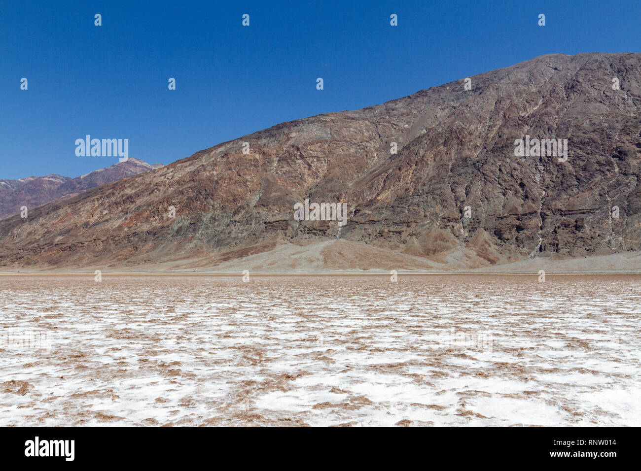 Autos entlang Badwater Road vor dem Fuß des Mt Perry, Badwater Basin, Death Valley National Park, California, United States. Stockfoto