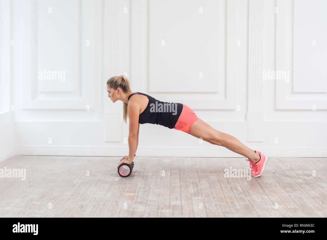 Profil Seitenansicht Portrait von athletischen blonde junge Frau in Passform mit schaumstoffrolle im Fitnessstudio Workout zu Verlust Gewicht zu und tun Plank. Rehabilitati Stockfoto