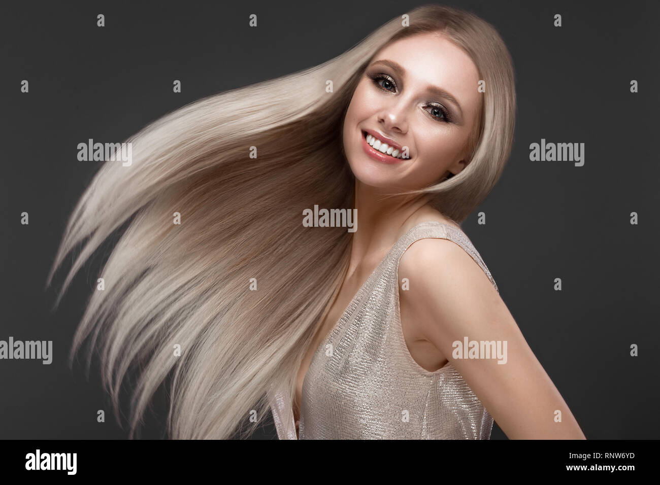 Schöne blondes Mädchen in bewegen perfekt glattes Haar mit klassischen Make-up. Beauty Gesicht. Stockfoto