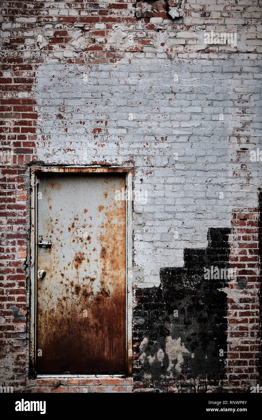 Altes rostiges Metall oder Stahl Tür in einer verwitterten Mauer geeignet für eine rustikale Hintergrund. Stockfoto