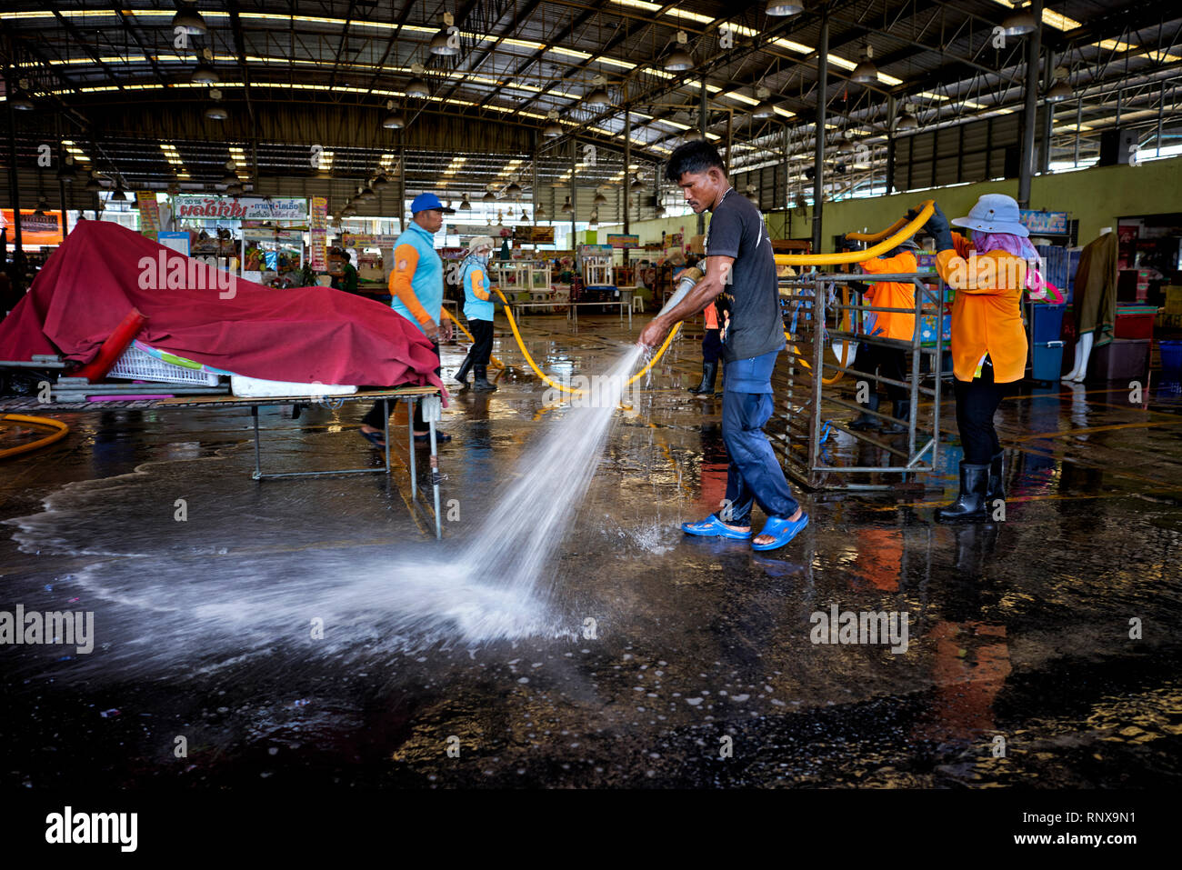 Straßenreinigung mit einem Gartenschlauch zu einem Thailand markt Veranstaltungsort. Stockfoto