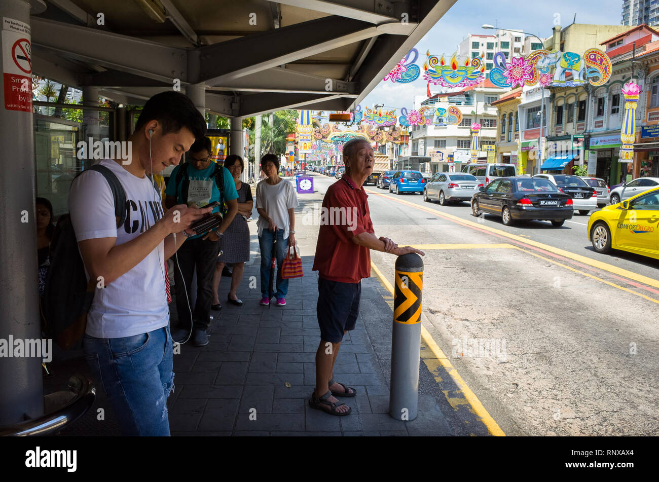 Fahrgäste des Busses neben Auto Verkehr auf Serangoon Rd warten, während Deepavali Festival in Llittle Indien - Singapur Stockfoto