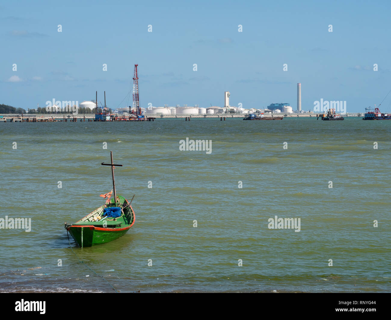 Einzelne Fischerboot am Strand mit einem wachsenden Industrial Estate in den Hintergrund in Map Ta Phut, Provinz Rayong in Thailand Stockfoto