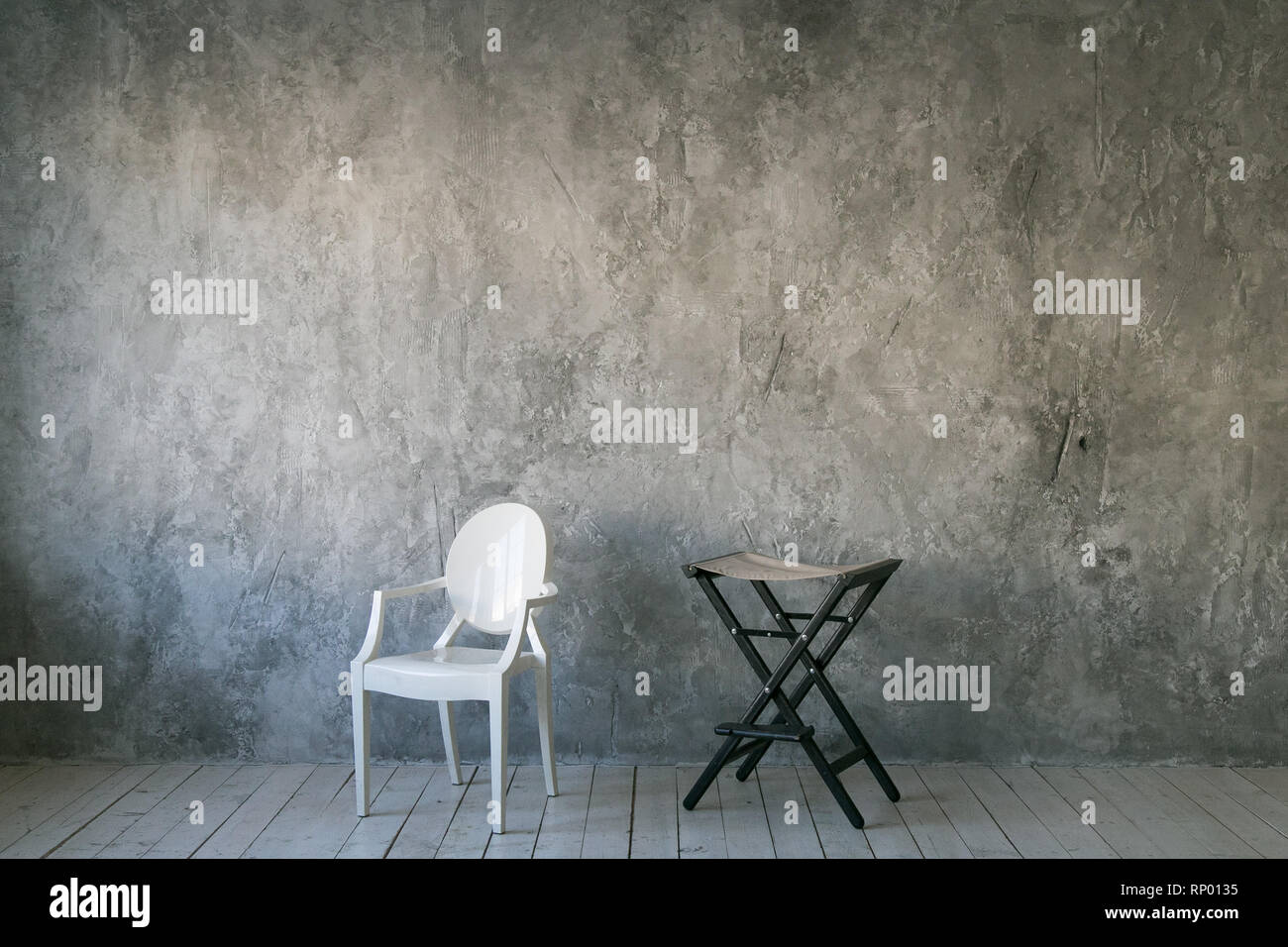 Zwei Stühle gegen die graue Betonwand. Zimmer im Loft-Stil. Holzboden. Tageslicht. Freier Platz für Text. Stockfoto