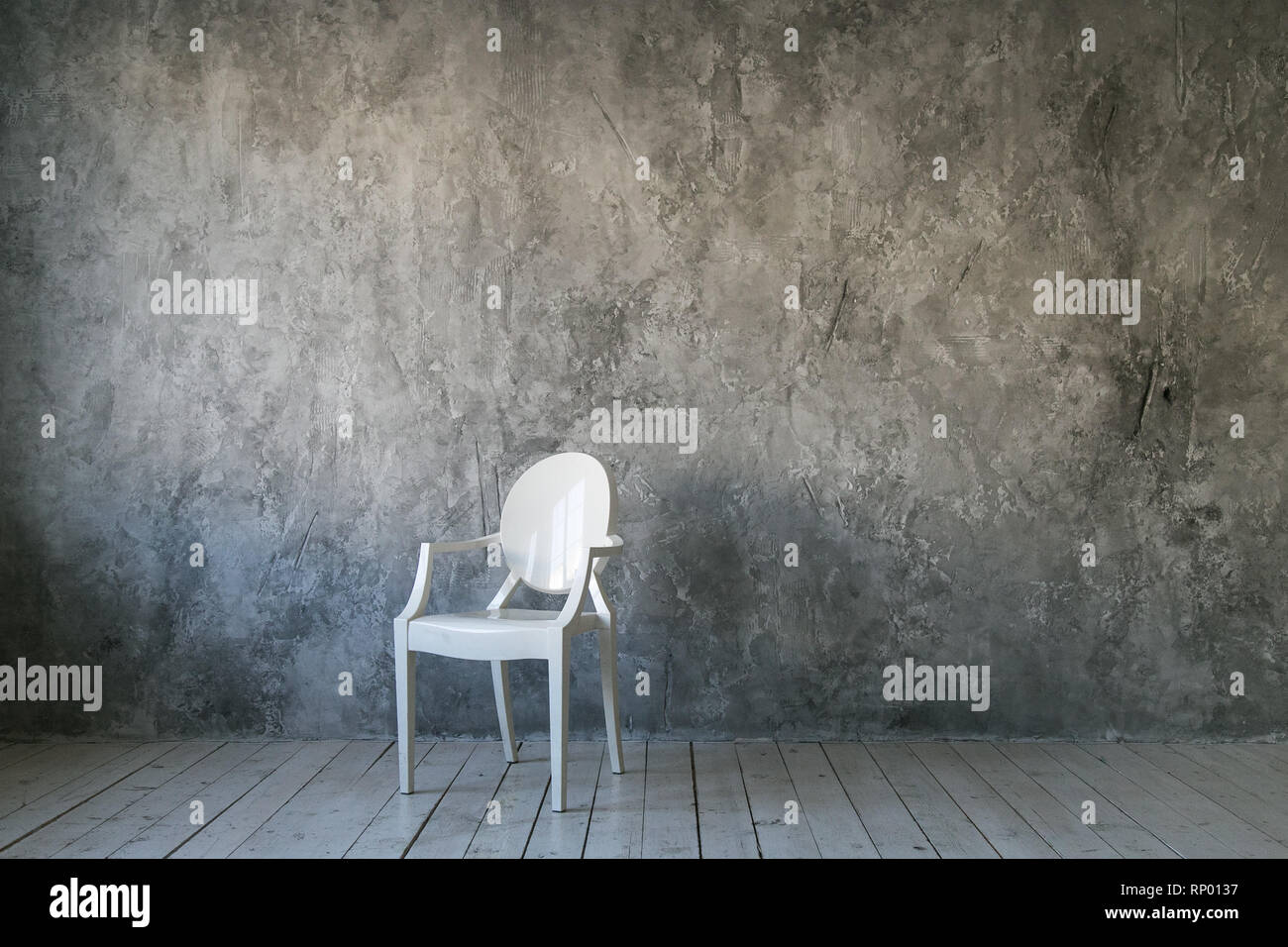 Weißer Kunststoff Stuhl auf Beton Wand Hintergrund. Loft Zimmer. Holzboden. Tageslicht. Freier Platz für Text. Stockfoto