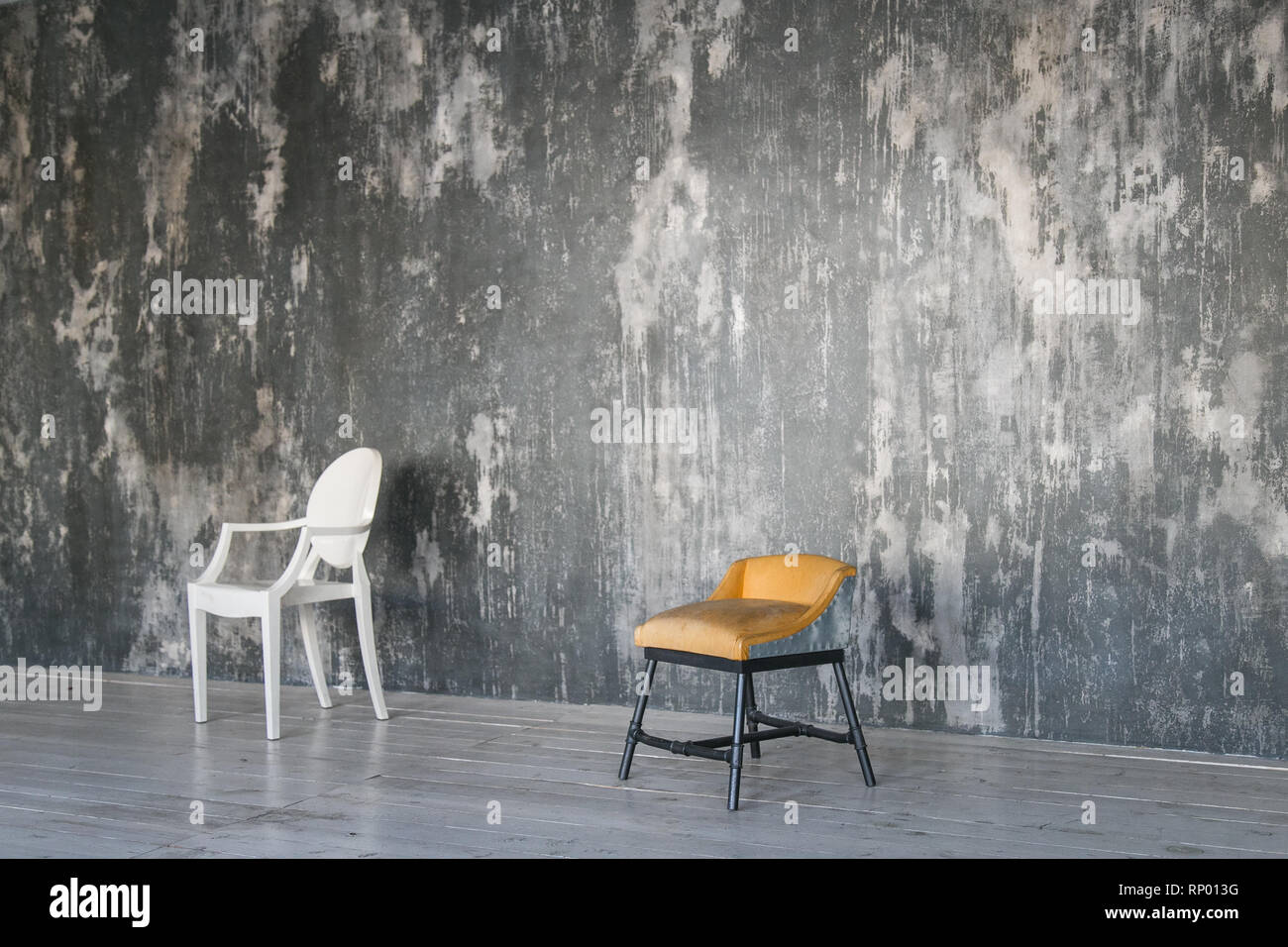 Zwei Stühle gegen die graue Betonwand. Zimmer im Loft-Stil. Holzboden. Tageslicht. Freier Platz für Text. Stockfoto