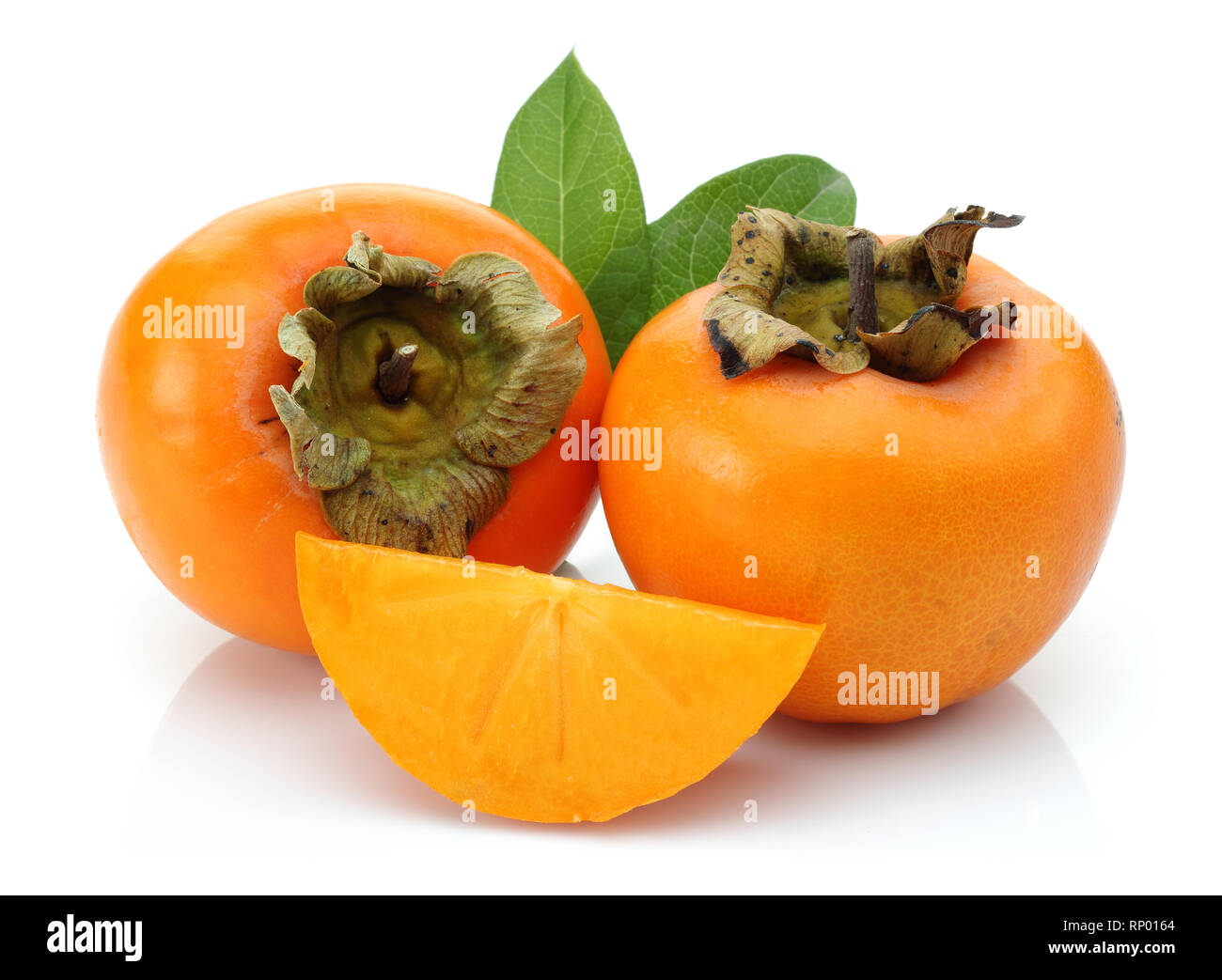 Scheibe und ganze Persimmon mit grünen Blättern auf weißem Hintergrund Stockfoto