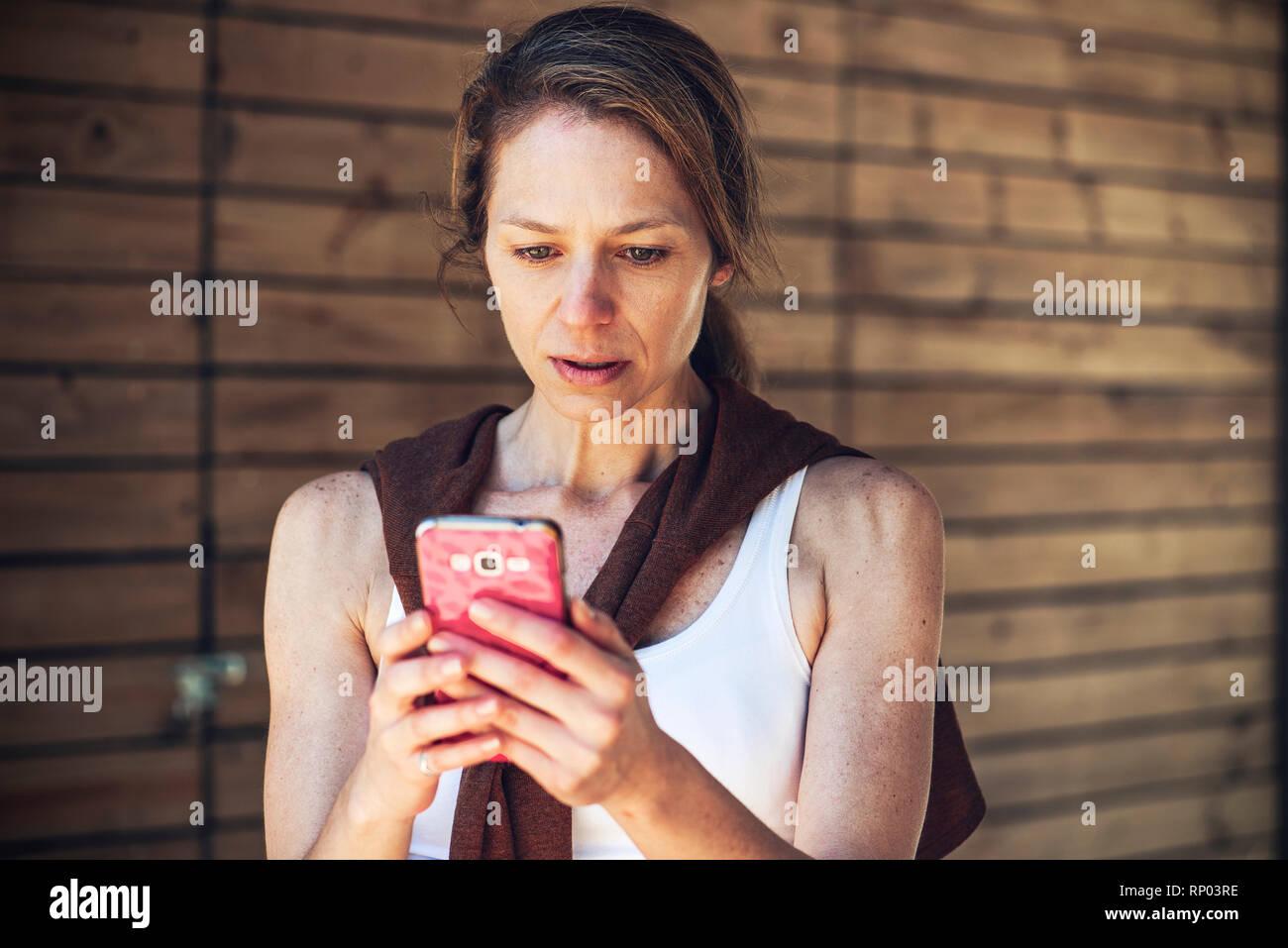 Ernsthafte reife Frau bei smart phone suchen Stockfoto