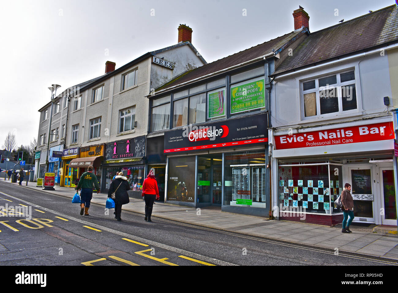 Eine Reihe von traditionellen Geschäften in der Innenstadt von Bridgend, Wales. Käufer zu Fuß entlang der Straße mit Einkaufstüten. Stockfoto