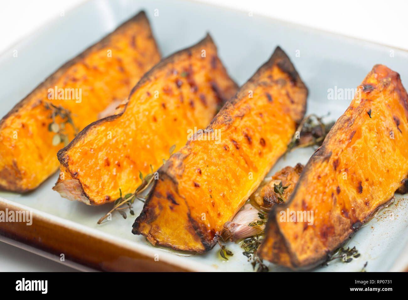 Vier Keile von butternut Kürbis mit der Haut nach links auf aus einem Supermarkt, der Braten im Ofen mit Olivenöl, zerdrückten Knoblauch gekauft und Stockfoto