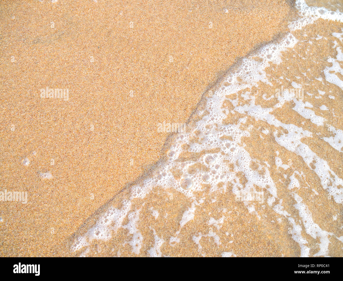 Schließen uo von Ocean Wave am Sandstrand Stockfoto