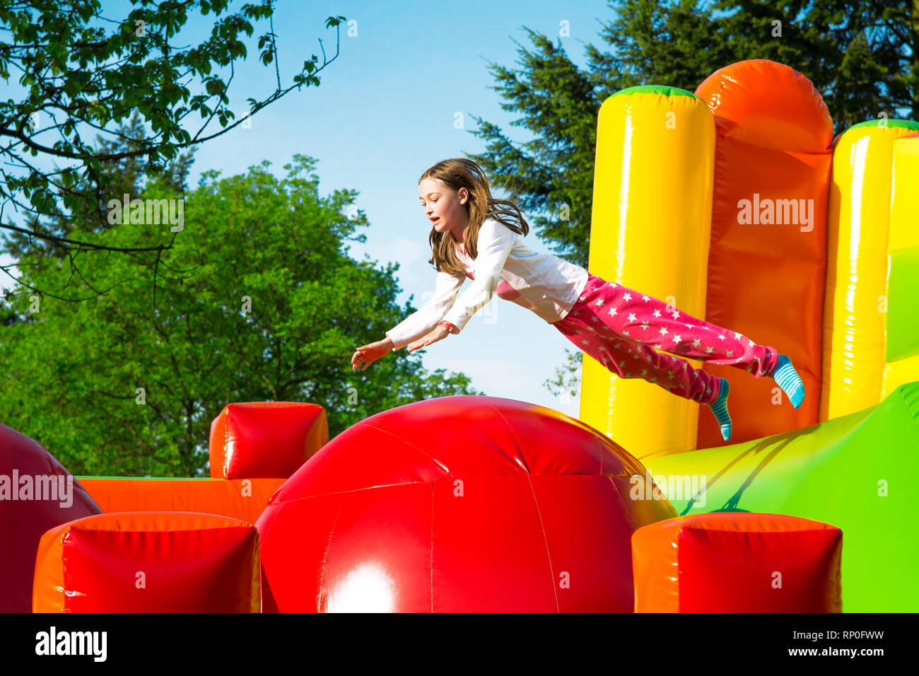 Gerne kleine Mädchen haben viel Spaß beim von Ball zu Ball springen auf ein Schloss aufpumpen. Stockfoto