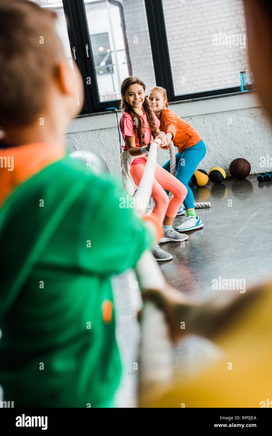 Begeisterte Kinder spielen Tauziehen in der Turnhalle Stockfoto