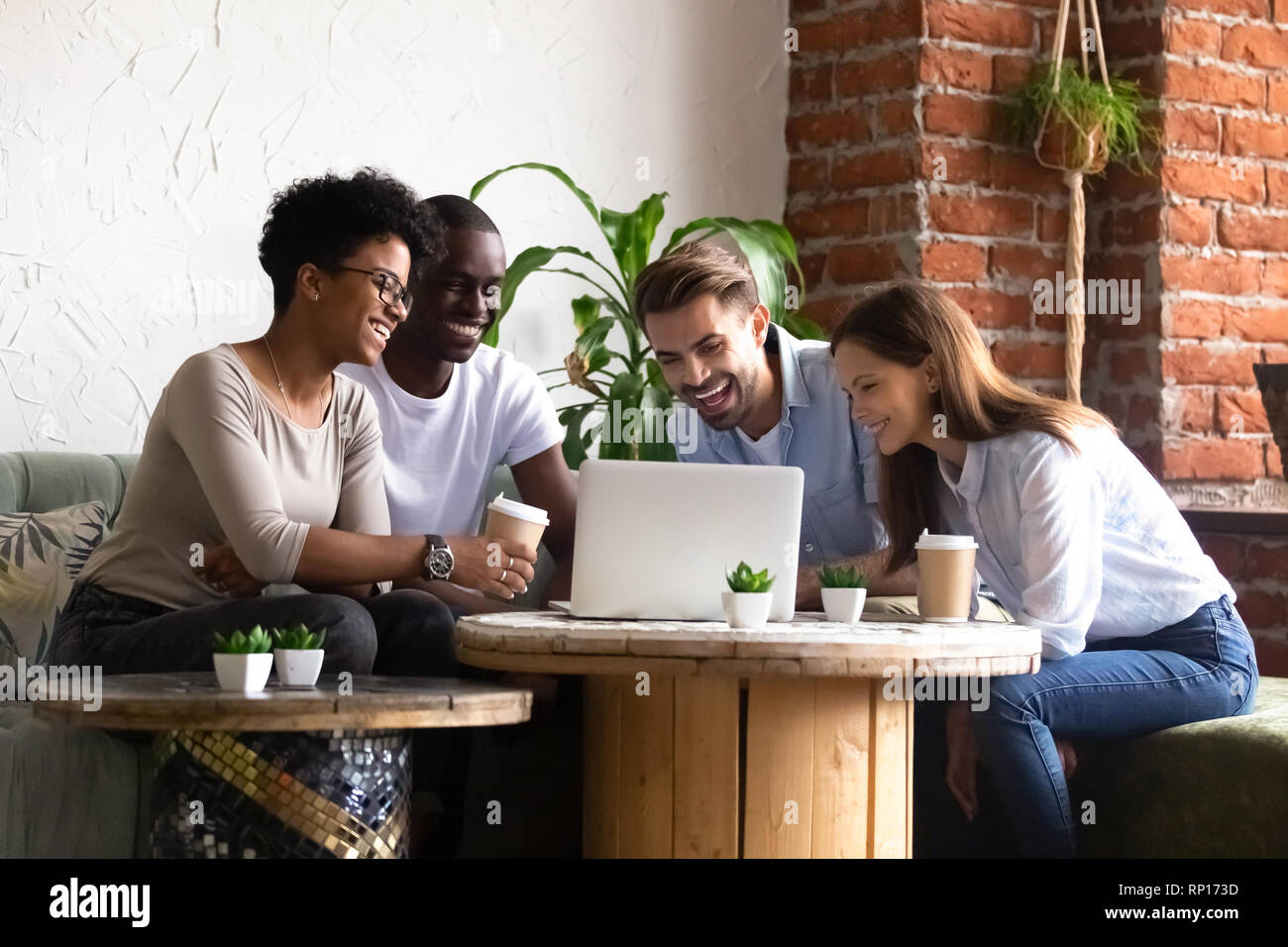 Diverse Freunde im Cafe sitzen gerade lustige Videos über Computer Stockfoto