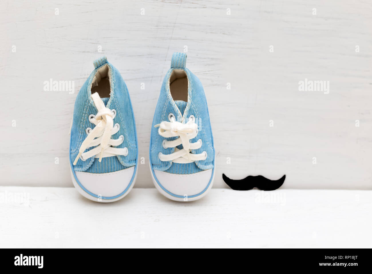 Little baby blue Sneakers für Junge und Schnurrbärte auf weißem Holz- Hintergrund Stockfoto